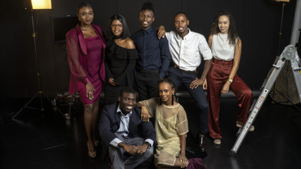 A group of seven people posing for a photo in a studio.